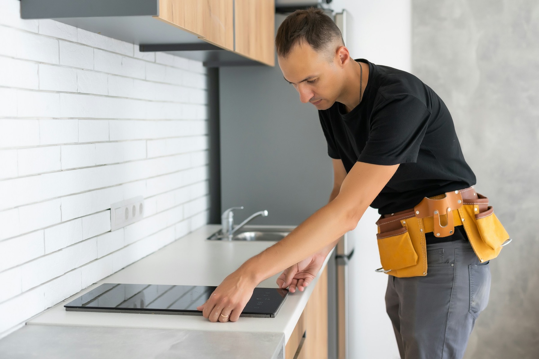 Licensed technician performing appliance installation in a residential kitchen